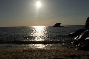 Sunset beach in Cape May New Jersey where you can get a great view of the sun going down across the ocean and the bay. The reflection of the sun on the water with the sunken ship looks so beautiful. photo