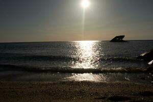 Sunset beach in Cape May New Jersey where you can get a great view of the sun going down across the ocean and the bay. The reflection of the sun on the water with the sunken ship looks so beautiful. photo