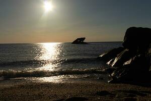 Sunset beach in Cape May New Jersey where you can get a great view of the sun going down across the ocean and the bay. The reflection of the sun on the water with the sunken ship looks so beautiful. photo