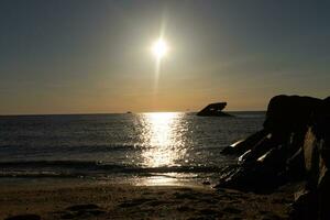 Sunset beach in Cape May New Jersey where you can get a great view of the sun going down across the ocean and the bay. The reflection of the sun on the water with the sunken ship looks so beautiful. photo