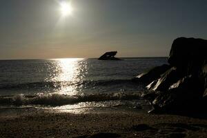 Sunset beach in Cape May New Jersey where you can get a great view of the sun going down across the ocean and the bay. The reflection of the sun on the water with the sunken ship looks so beautiful. photo