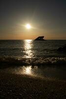 Sunset beach in Cape May New Jersey where you can get a great view of the sun going down across the ocean and the bay. The reflection of the sun on the water with the sunken ship looks so beautiful. photo