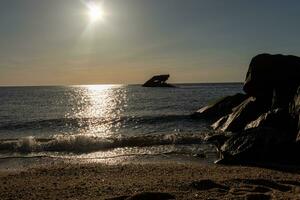 Sunset beach in Cape May New Jersey where you can get a great view of the sun going down across the ocean and the bay. The reflection of the sun on the water with the sunken ship looks so beautiful. photo