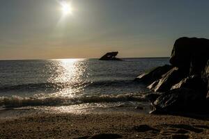 Sunset beach in Cape May New Jersey where you can get a great view of the sun going down across the ocean and the bay. The reflection of the sun on the water with the sunken ship looks so beautiful. photo