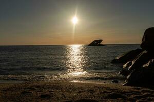 Sunset beach in Cape May New Jersey where you can get a great view of the sun going down across the ocean and the bay. The reflection of the sun on the water with the sunken ship looks so beautiful. photo