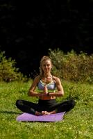 Fitness woman sitting in a yoga pose in a park. photo