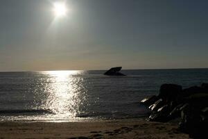 Sunset beach in Cape May New Jersey where you can get a great view of the sun going down across the ocean and the bay. The reflection of the sun on the water with the sunken ship looks so beautiful. photo