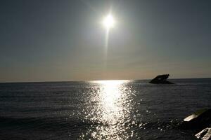 Sunset beach in Cape May New Jersey where you can get a great view of the sun going down across the ocean and the bay. The reflection of the sun on the water with the sunken ship looks so beautiful. photo