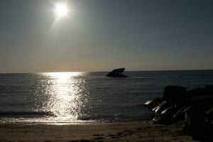 Sunset beach in Cape May New Jersey where you can get a great view of the sun going down across the ocean and the bay. The reflection of the sun on the water with the sunken ship looks so beautiful. photo