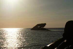 Sunset beach in Cape May New Jersey where you can get a great view of the sun going down across the ocean and the bay. The reflection of the sun on the water with the sunken ship looks so beautiful. photo