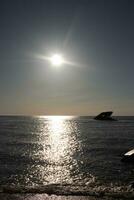 Sunset beach in Cape May New Jersey where you can get a great view of the sun going down across the ocean and the bay. The reflection of the sun on the water with the sunken ship looks so beautiful. photo