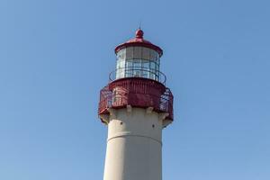 This is Cape May point lighthouse in New Jersey. I love the white look of its tower and the red top to it that stands out from so many. This beacon of hope helps people at sea to navigate. photo