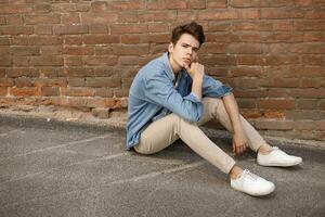 Closeup of man in white T-shirt on brick wall background photo