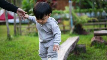 A boy  walks on a log keeping balance in the park. video