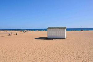 a beach hut on a sandy beach with people walking around photo