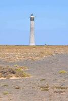 a lighthouse on a barren field with a blue sky photo