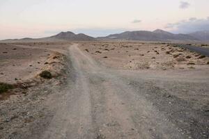 a dirt road in the desert with mountains in the background photo