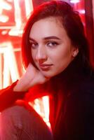 Portrait of a girl on the background of a neon sign of a shop window photo