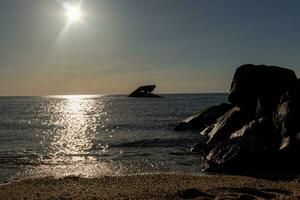 Sunset beach in Cape May New Jersey where you can get a great view of the sun going down across the ocean and the bay. The reflection of the sun on the water with the sunken ship looks so beautiful. photo