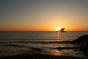 Sunset beach in Cape May New Jersey where you can get a great view of the sun going down across the ocean and the bay. The reflection of the sun on the water with the sunken ship looks so beautiful. photo