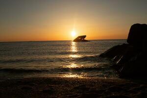 Sunset beach in Cape May New Jersey where you can get a great view of the sun going down across the ocean and the bay. The reflection of the sun on the water with the sunken ship looks so beautiful. photo