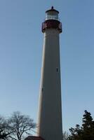 This is Cape May point lighthouse in New Jersey. I love the white look of its tower and the red top to it that stands out from so many. This beacon of hope helps people at sea to navigate. photo