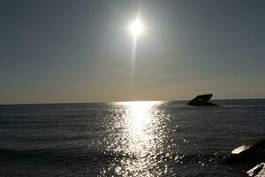 Sunset beach in Cape May New Jersey where you can get a great view of the sun going down across the ocean and the bay. The reflection of the sun on the water with the sunken ship looks so beautiful. photo