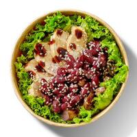 Salad with lettuce, chicken fillet, baked mushrooms and red beans, teriyaki sauce and sesame in cardboard bowl on white photo