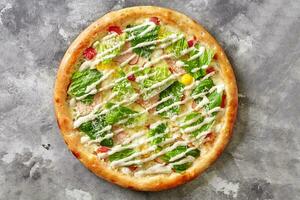 Pizza with smoked chicken, tomatoes, quail eggs, romaine lettuce, Caesar sauce and grated parmesan photo