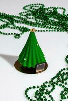 Christmas tree shaped pastry and green beads on white photo