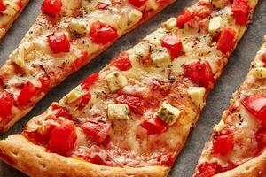 Slices of pizza with mozzarella, tomatoes, blue cheese and dried Italian herbs photo