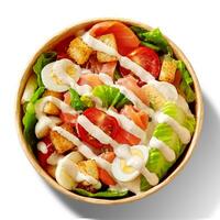 Caesar salad with lettuce, tomatoes, quail eggs, croutons and smoked salmon in paper bowl isolated on white photo
