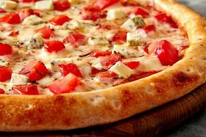 Pizza with mozzarella, tomatoes, Gorgonzola and dried herbs on wooden serving board photo