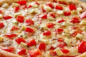 Closeup of pizza with tomatoes and blue cheese on melted mozzarella with dried herbs photo