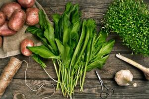 Raw potatoes in a linen bag, spinach, sorrel, greens and garlic, food background, top view photo