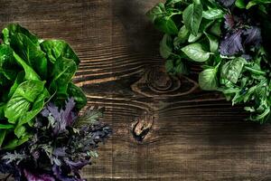 Variety of fresh organic herbs on wooden background. Freshly harvested herbs including basil, arugula. Top view. Copy space. photo