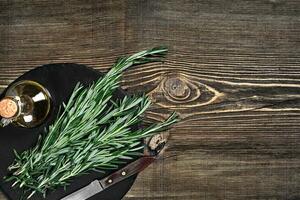 Branches of rosemary on gray wooden table. Rosemary on cutting board. Rustic style, fresh organic herbs. photo