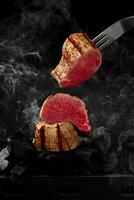 Pieces of beef tenderloin cooking on grill over smoking embers photo