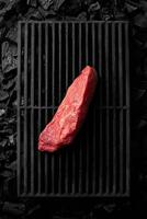 Piece of lean pork tenderloin on black cast iron grill grate over cold coals photo