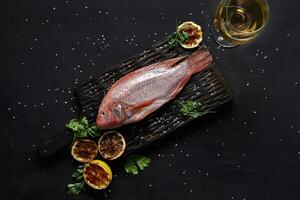 Delicious fresh raw red seafood fish mullet on dark table, top view photo