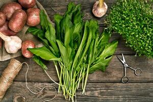 Raw potatoes in a linen bag, spinach, sorrel, greens and garlic, food background, top view photo