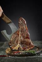 Grilled T-Bone Steak with salt and pepper on cutting board on dark background photo
