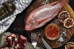 Delicious fresh raw red seafood fish mullet on wooden cutting board, top view photo