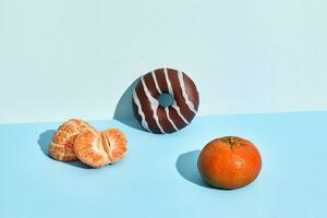 Composition of fresh fruits and sweets, donut and mandarin, half of peeled mandarin photo