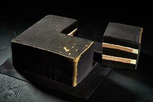 Black square cake with gold edges. Dark background. The view from the top. photo