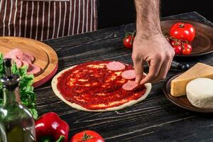 cocinar en el cocina poniendo el ingredientes en el Pizza. Pizza concepto. producción y entrega de alimento. foto