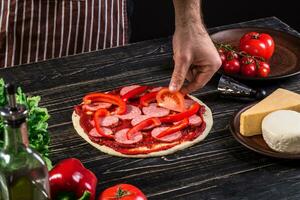 cocinar en el cocina poniendo el ingredientes en el Pizza. Pizza concepto. producción y entrega de alimento. foto