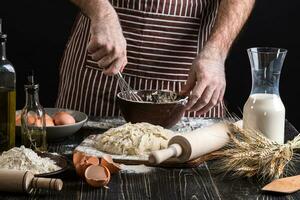 Male chef whipping eggs in the bakery on wooden table. Ingredients for cooking flour products or dough photo