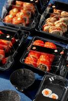 Set of sushi rolls packed in plastic takeaway containers with ginger and soy sauce photo