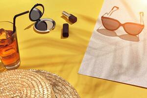 Straw beach woman's hat and sun glasses, top view yellow and white paper background with shadow from a palm leaf. Sun flare photo